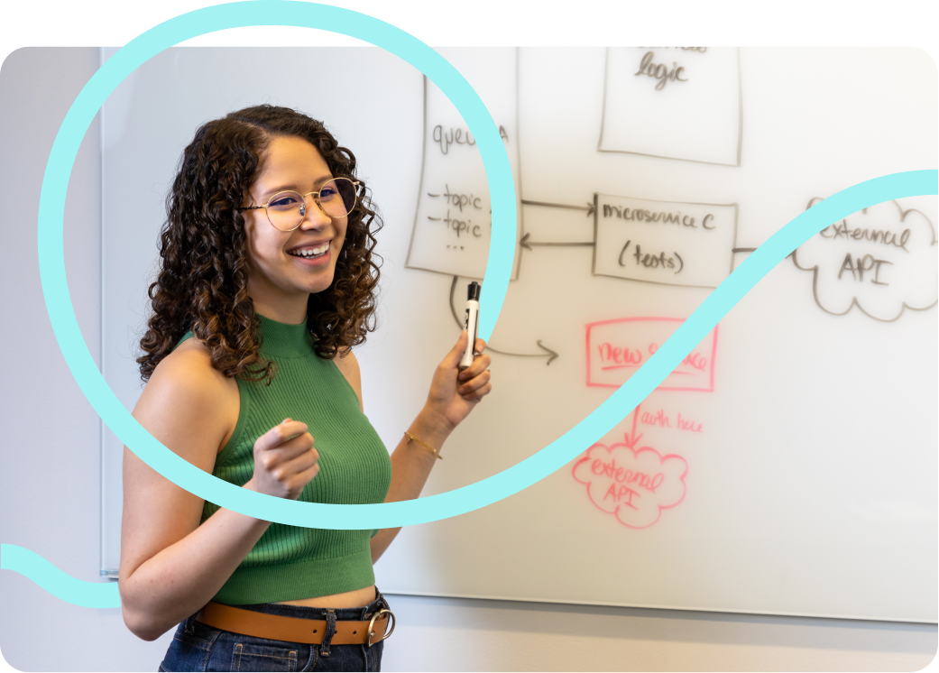 一位女性工程师在白板上绘制微服务架构图。