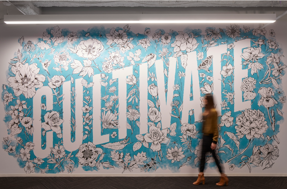 办公室墙上的一幅壁画，在明亮的蓝色背景上，围绕着“培养”一词的花卉插图。
