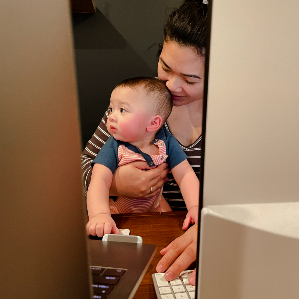 一位斯普劳特公司的女性员工抱着她的小孩在笔爱游戏体育官网首页记本电脑上工作。
