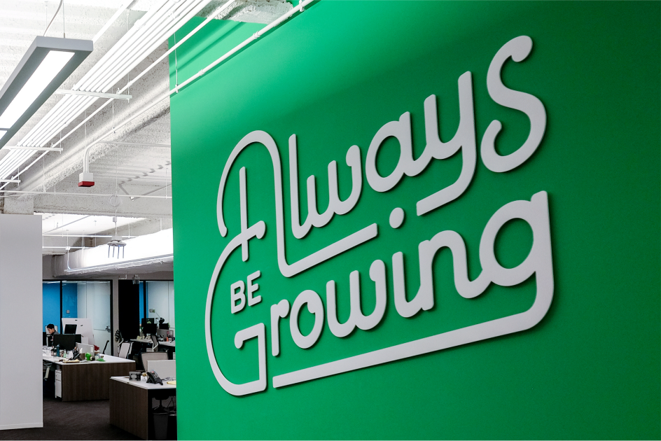 一幅绿色的壁画，上面用白色的曲线字体写着“永远在成长”。
