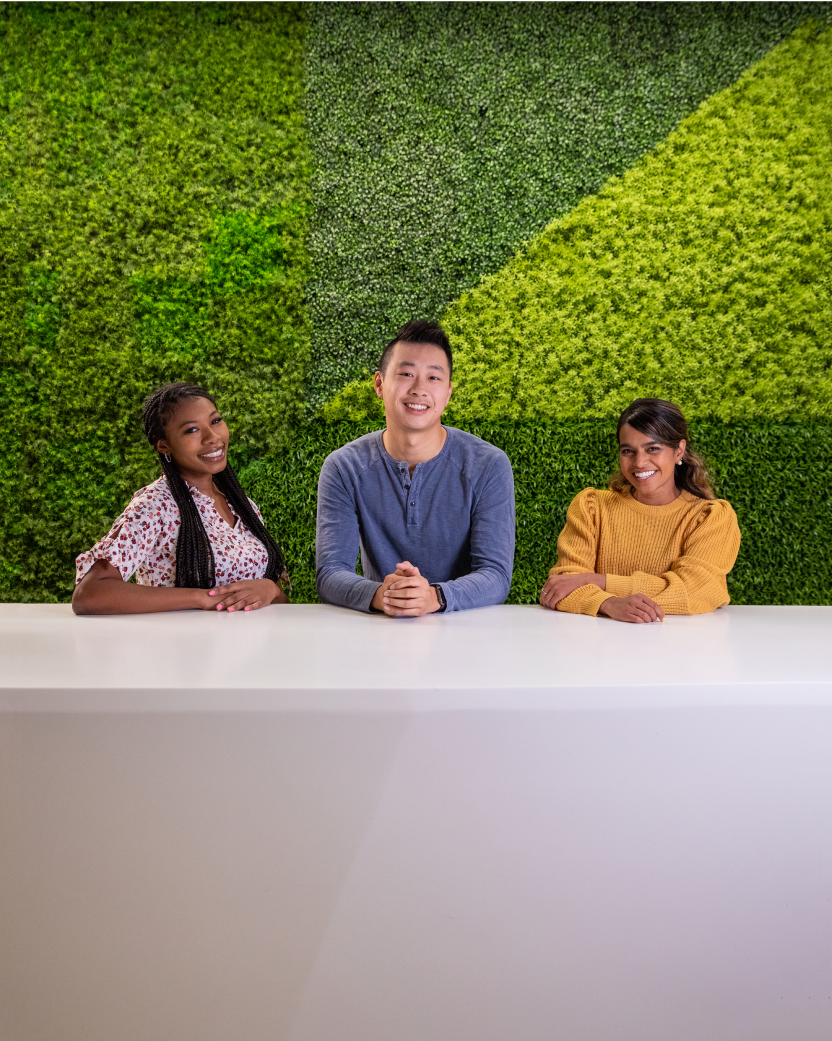 种族和性别多元化斯普劳特公司的员工在办公室亮绿色的草墙前爱游戏体育官网首页微笑着摆姿势。