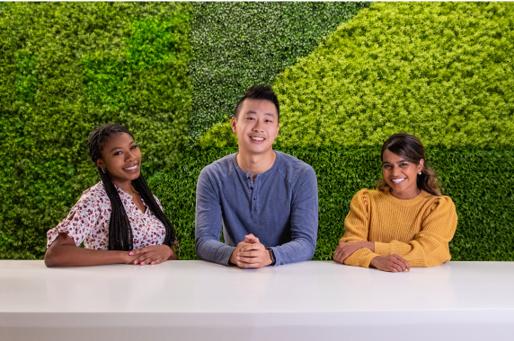 种族和性别多元化斯普劳特公司的员工在办公室亮绿色的草墙前爱游戏体育官网首页微笑着摆姿势。